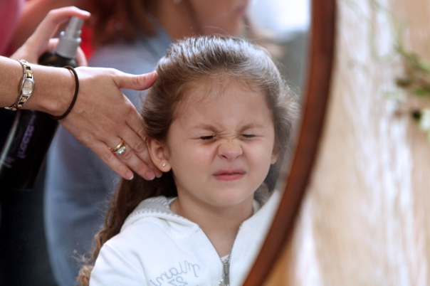 The little flower girl gets a finishing touch of hairspray.